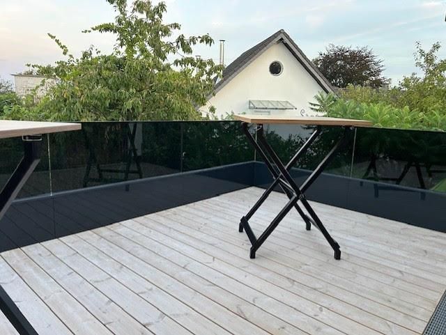 Eine Holzterrasse mit Tisch und Stühlen darauf
