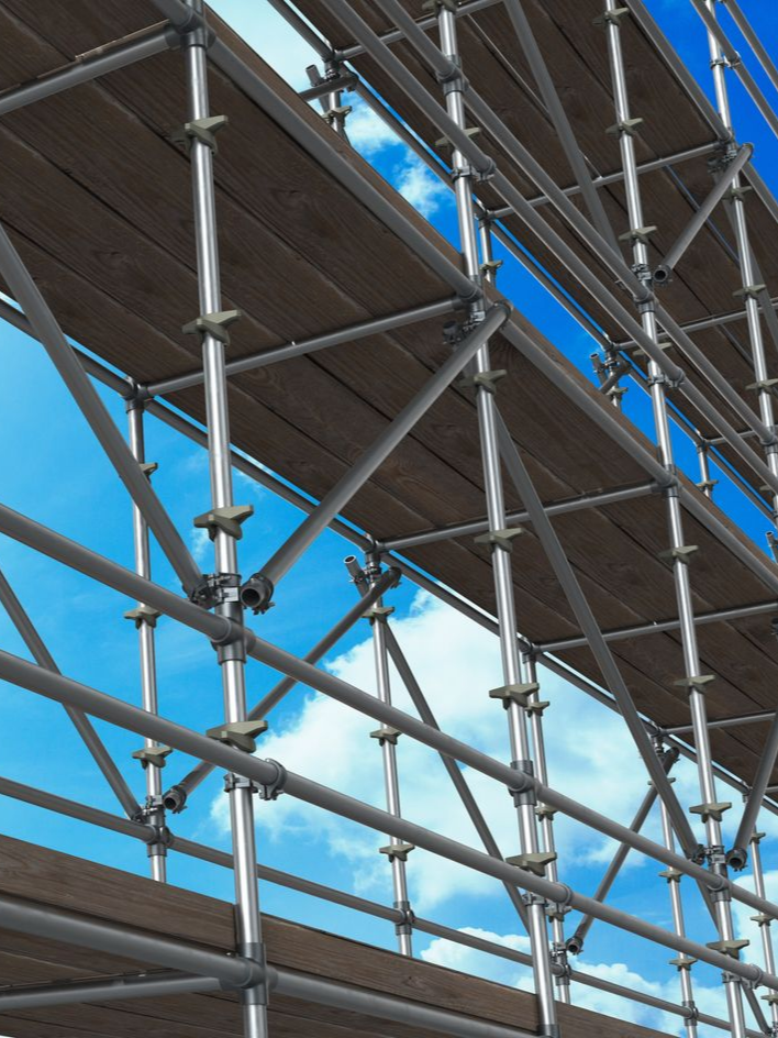 Échafaudages se détachant sur un ciel bleu nuageux ; planches de bois entre des supports métalliques.