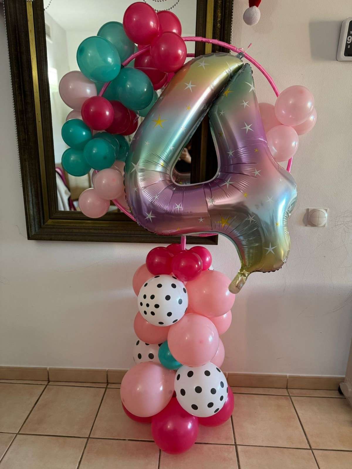 Un arreglo de globos que incluye un gran globo iridiscente con el número 