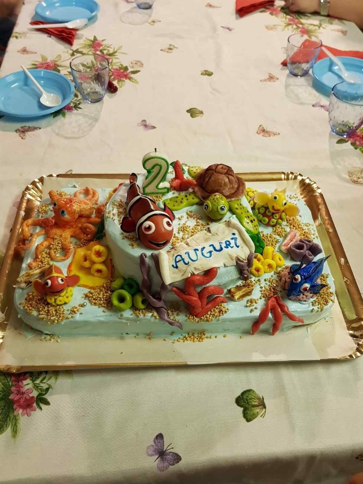 Una tarta de cumpleaños con temática submarina que incluye un pez payaso, una tortuga y un pulpo, decorada con el nombre 