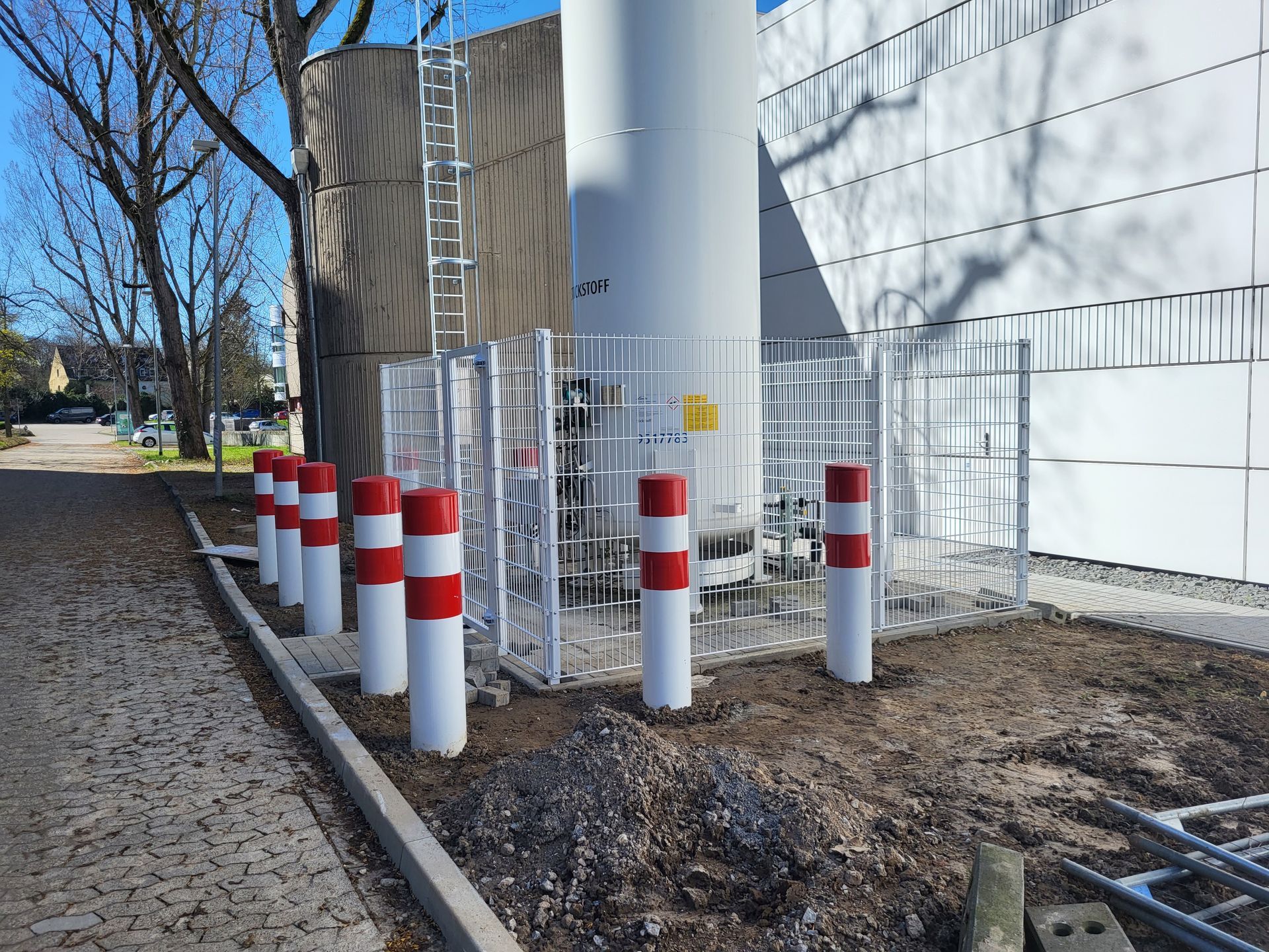 Ein eingezäunter Bereich mit roten und weißen Stangen vor einem Gebäude.