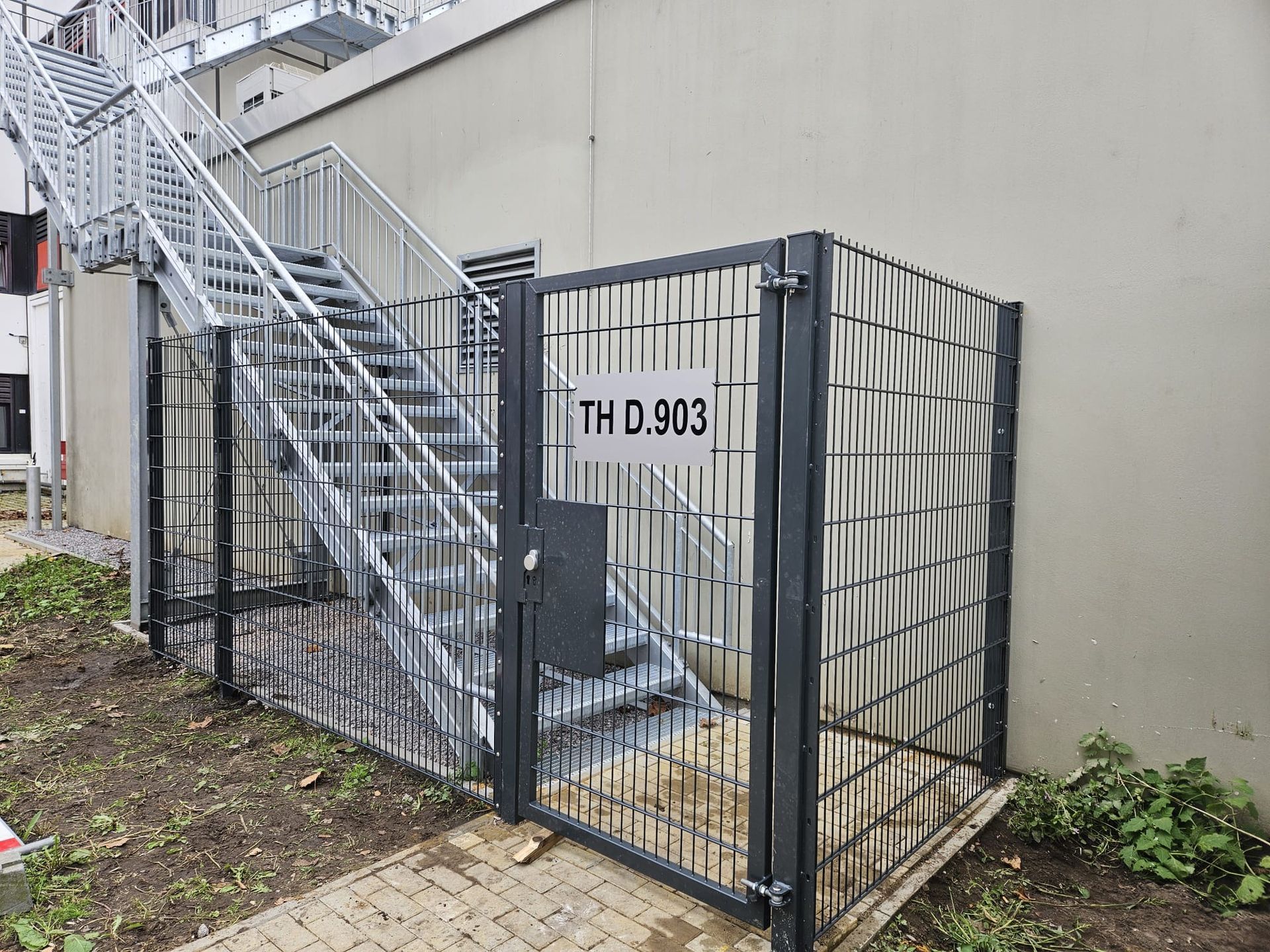 Eine Treppe hinter einem Zaun mit einem Tor.