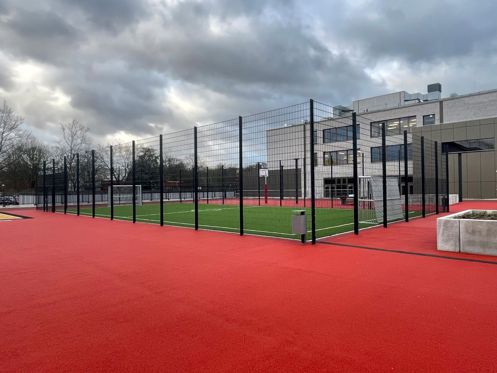 Ein schwarzer Zaun mit einem gelben Bagger im Hintergrund.