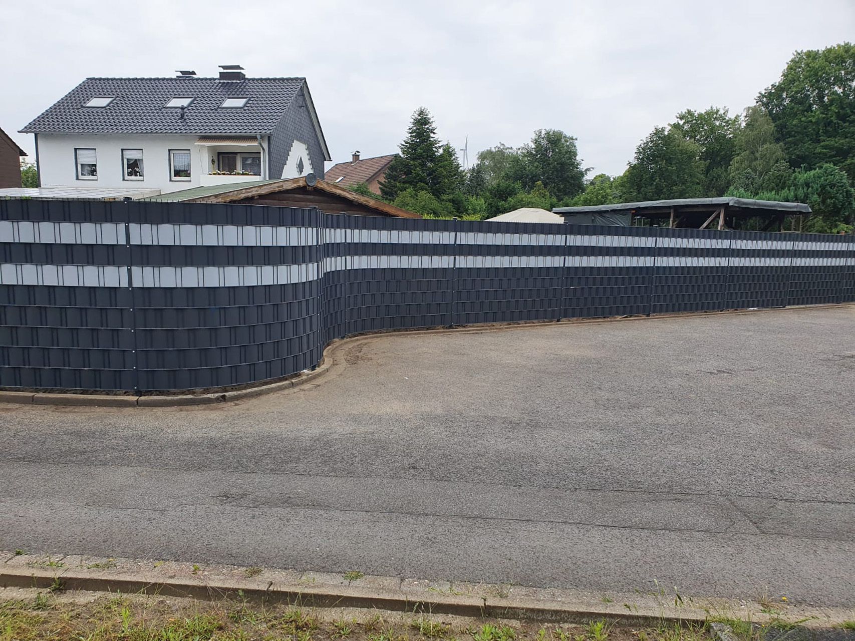 Ein Mann füllt mit einer Schaufel ein Loch im Boden mit Kies zur Befestigung des Pfostens.