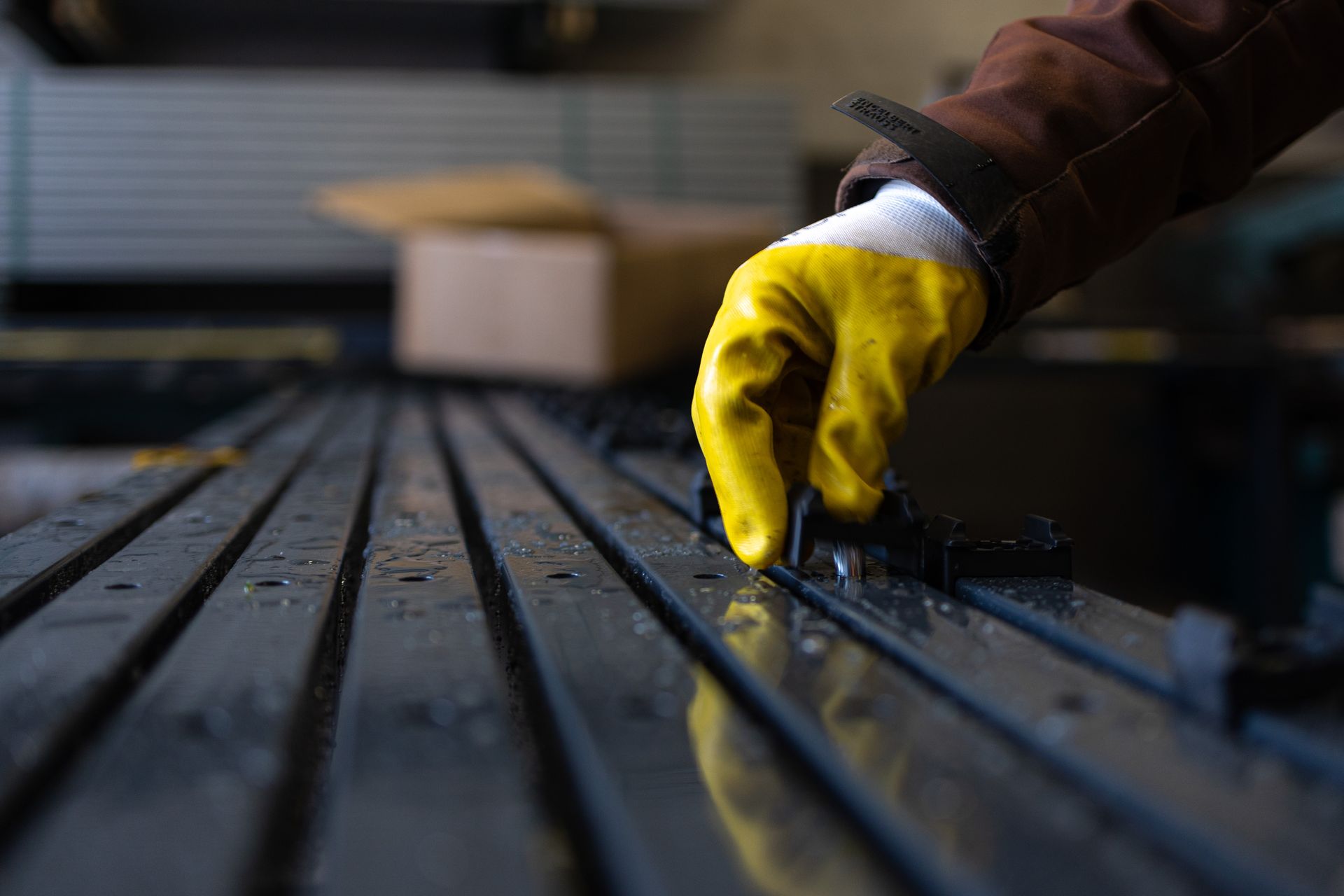 Eine Person mit gelben Handschuhen arbeitet an einem Zaun.