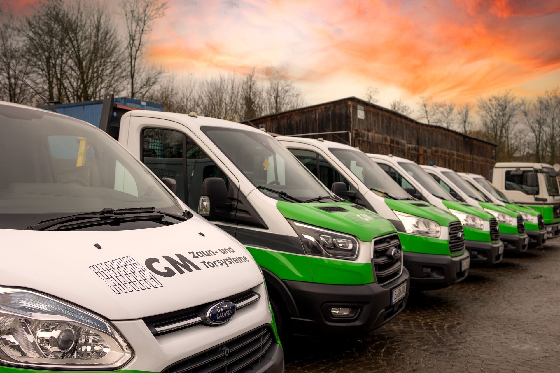 Auf einem Parkplatz steht eine Reihe grün-weiß-folierter Firmenfahrzeuge von GM.