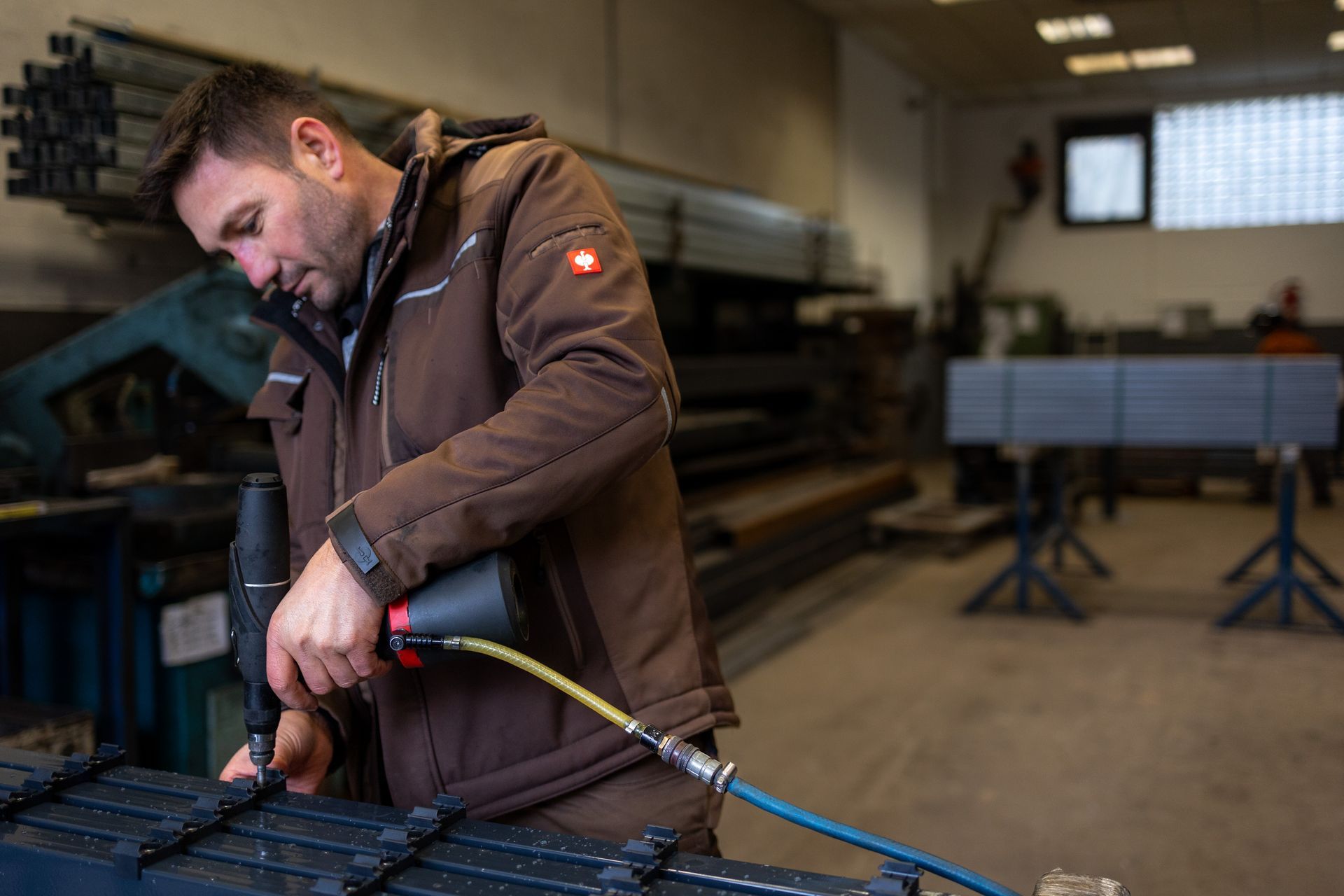 Ein Mitarbeiter bearbeitet in einer Halle an einem Metallzaun.