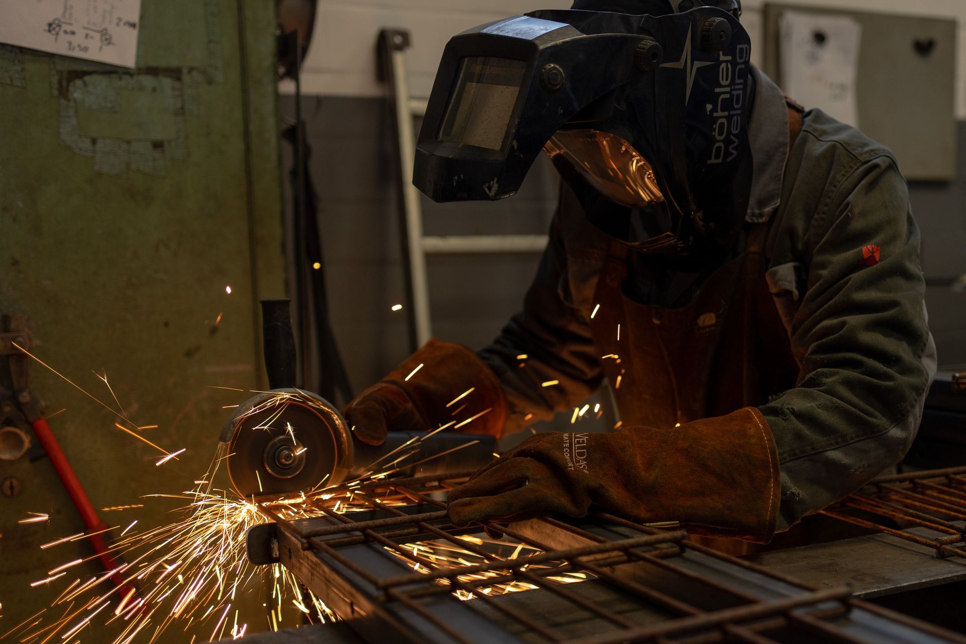 Ein Mann mit einer Schweißmaske schneidet ein Stück Metall.