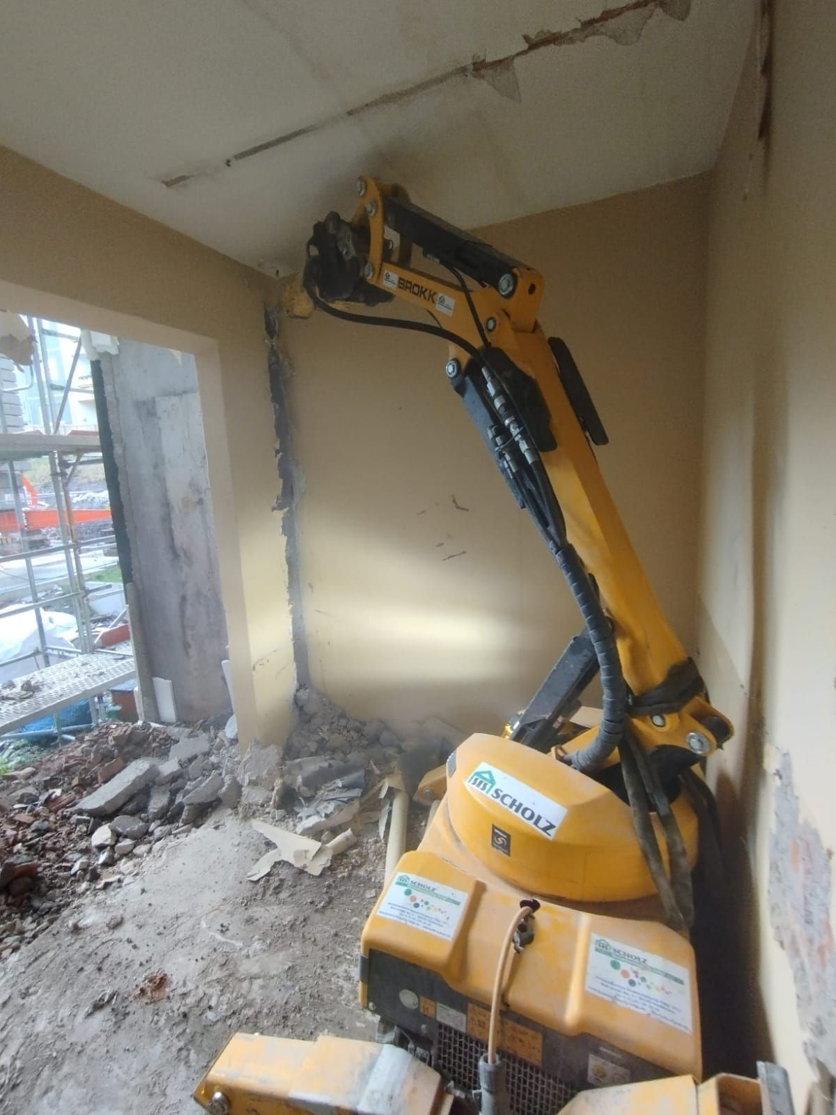 Ein gelber Bagger steht in einem Raum mit einem Loch in der Wand