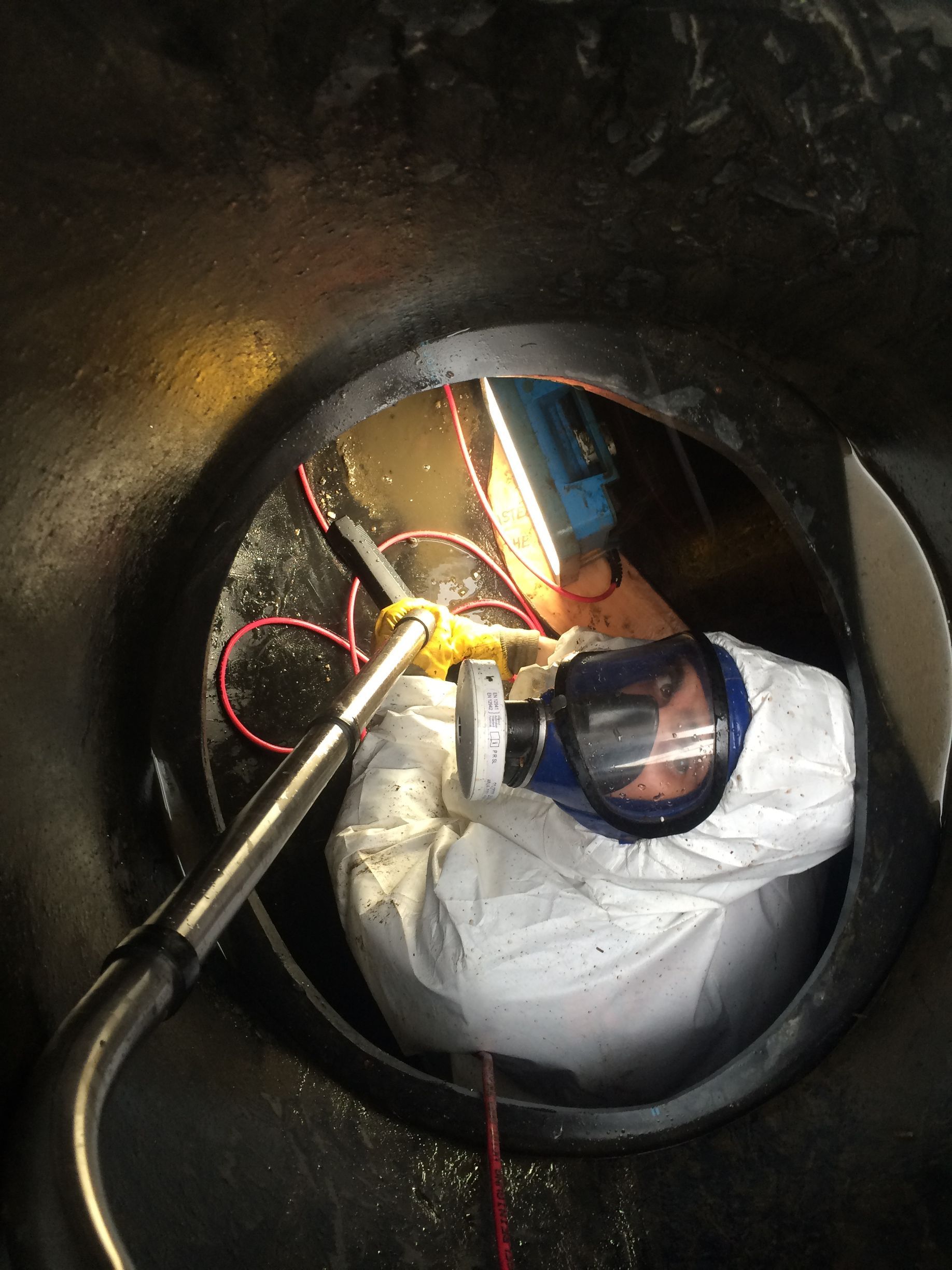 Ein Mann mit einer Gasmaske arbeitet in einem Schacht.