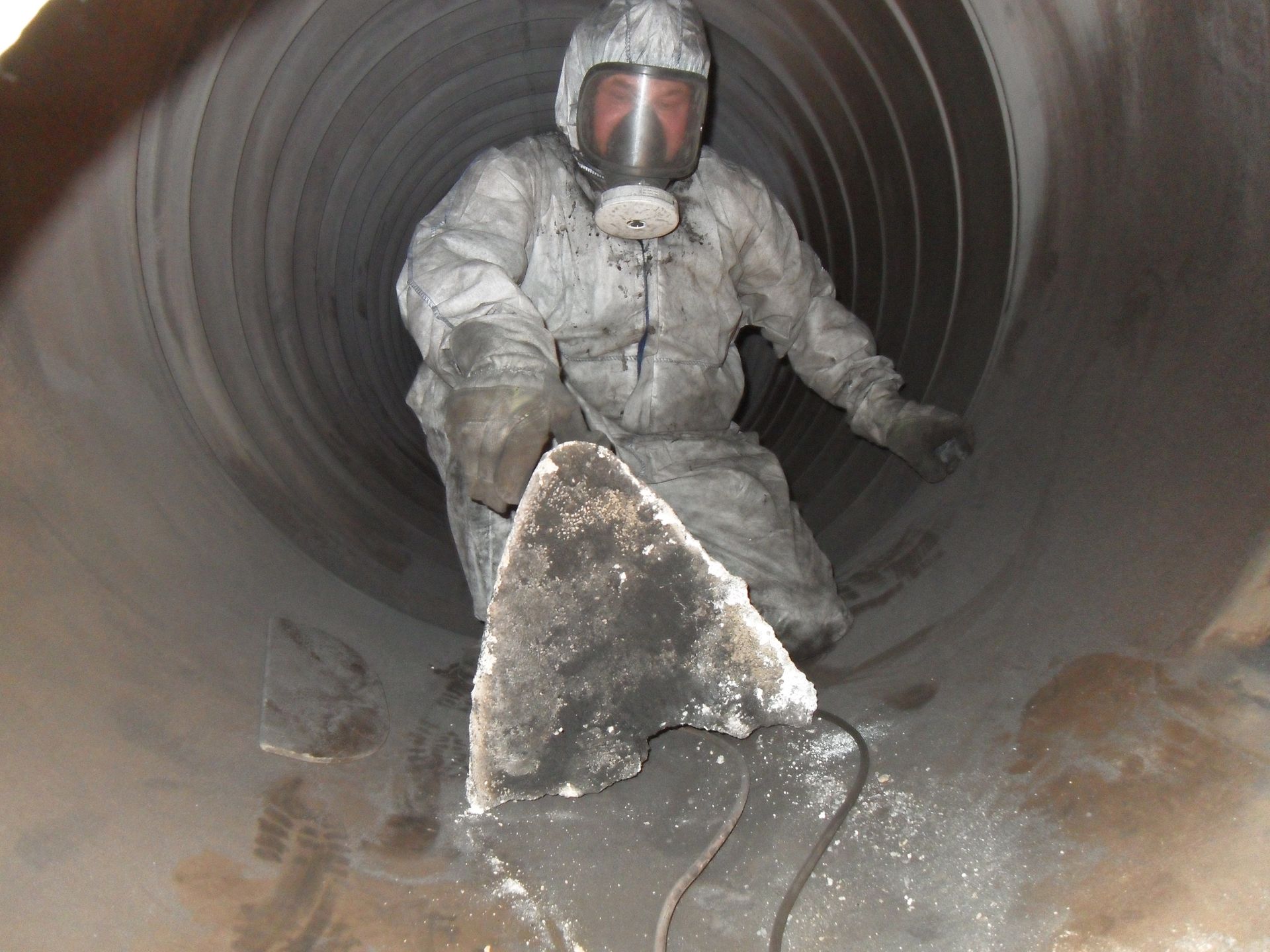 Ein Mann mit einer Gasmaske arbeitet an einem Rohr
