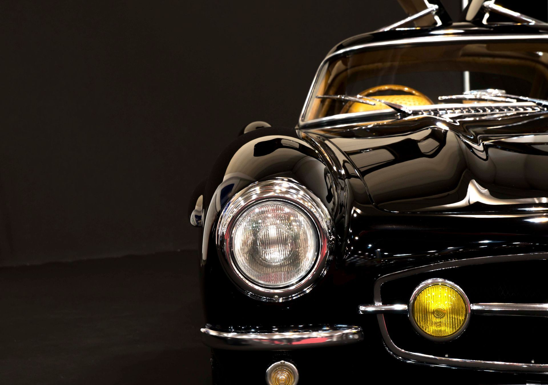 Eine Nahaufnahme eines schwarzen Autos mit einem gelben Licht an der Vorderseite.