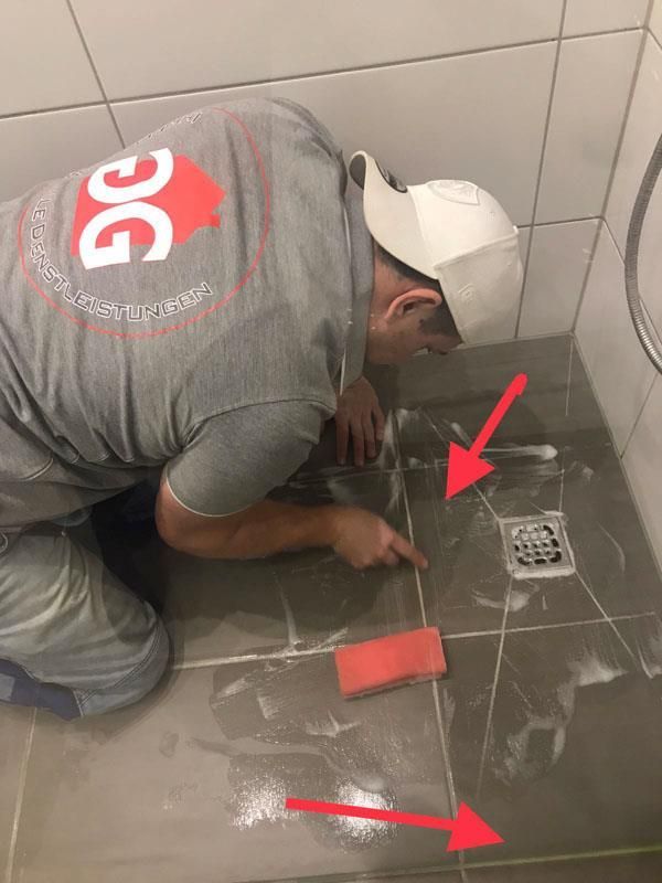 Ein Mann kniet in einem Badezimmer und putzt den Boden.