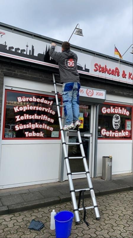 Ein Mann steht auf einer Leiter vor einem Geschäft.