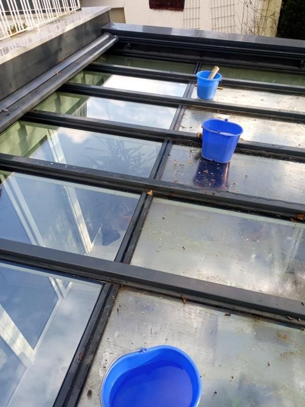 Zwei blaue Eimer stehen auf einem Glasdach