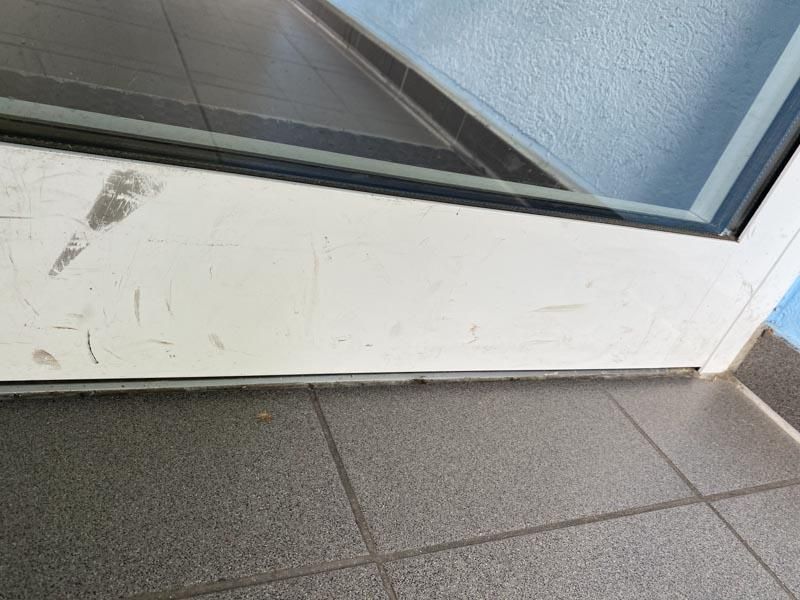 Eine weiße Tür steht auf einem gefliesten Boden neben einer blauen Wand