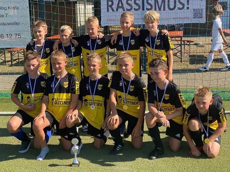 Eine Gruppe junger Jungen posiert auf einem Fußballfeld für ein Foto.