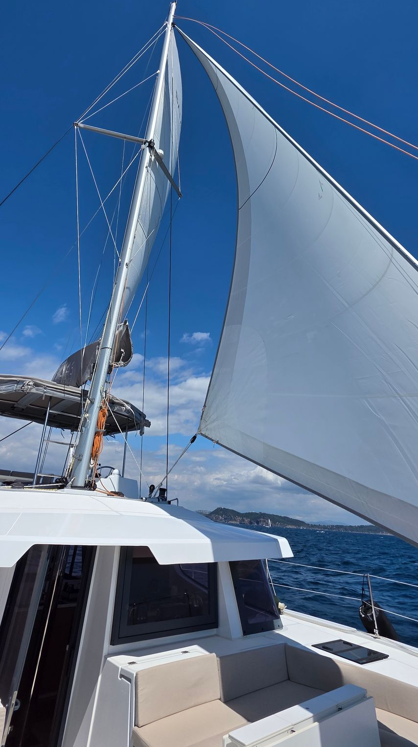 Navigation en catamaran dans une eau turquoise près d'un rivage rocheux.