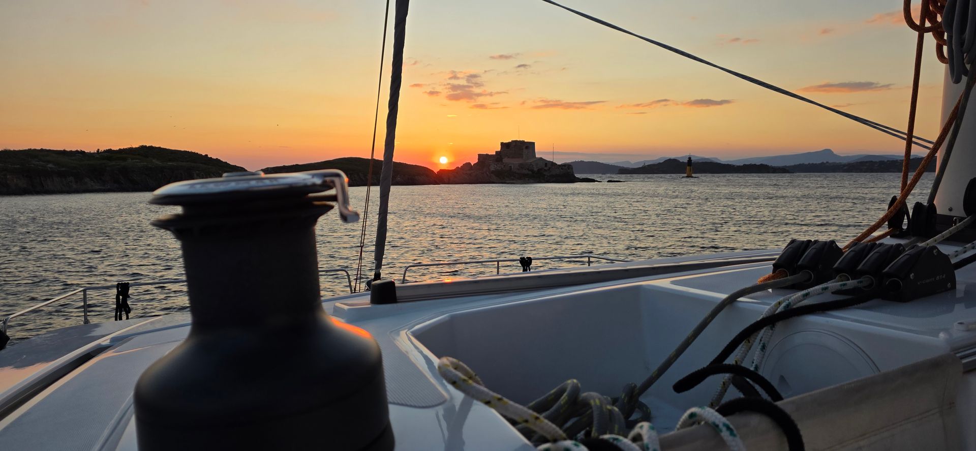 Pont d'un voilier avec un coucher de soleil sur l'eau.