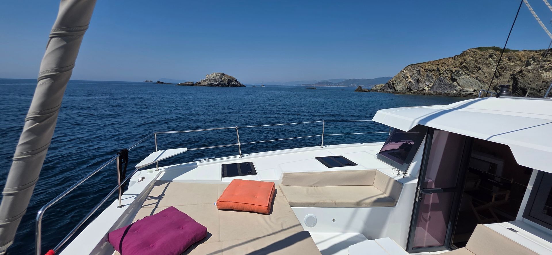 Catamaran blanc naviguant sur une eau turquoise, vue du dessus.