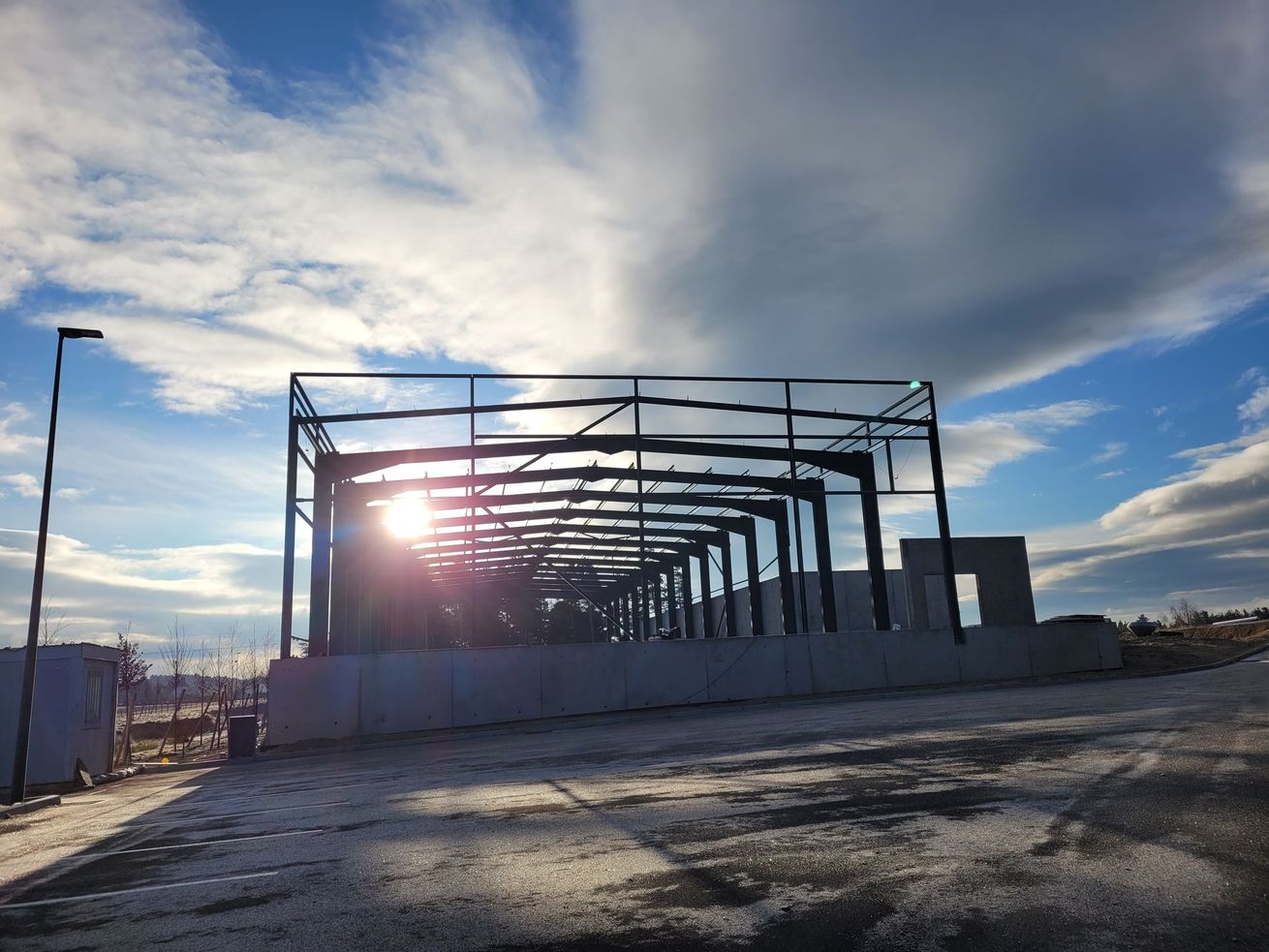 Structure métallique ensoleillée en construction au bord d'une route goudronnée au crépuscule