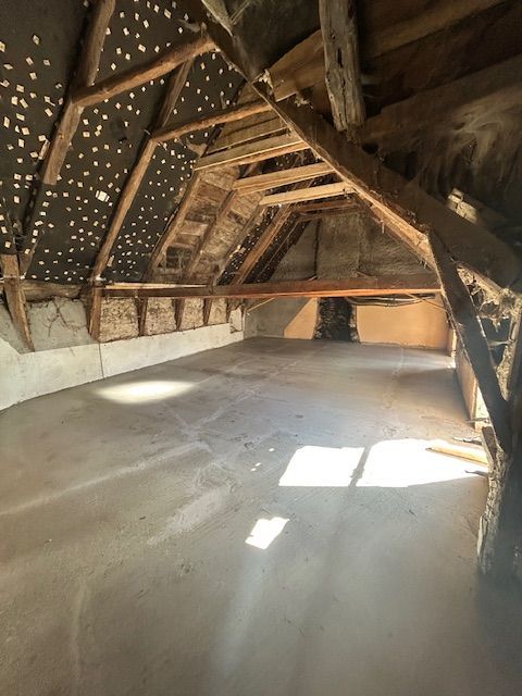 Grenier vide avec poutres apparentes et lumière du soleil sur le sol