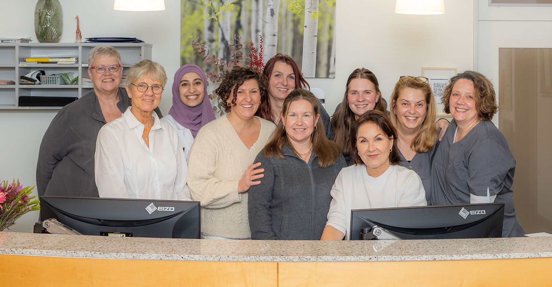 Mitarbeiter der Praxis Steins stehen hinterm Empfangstresen.