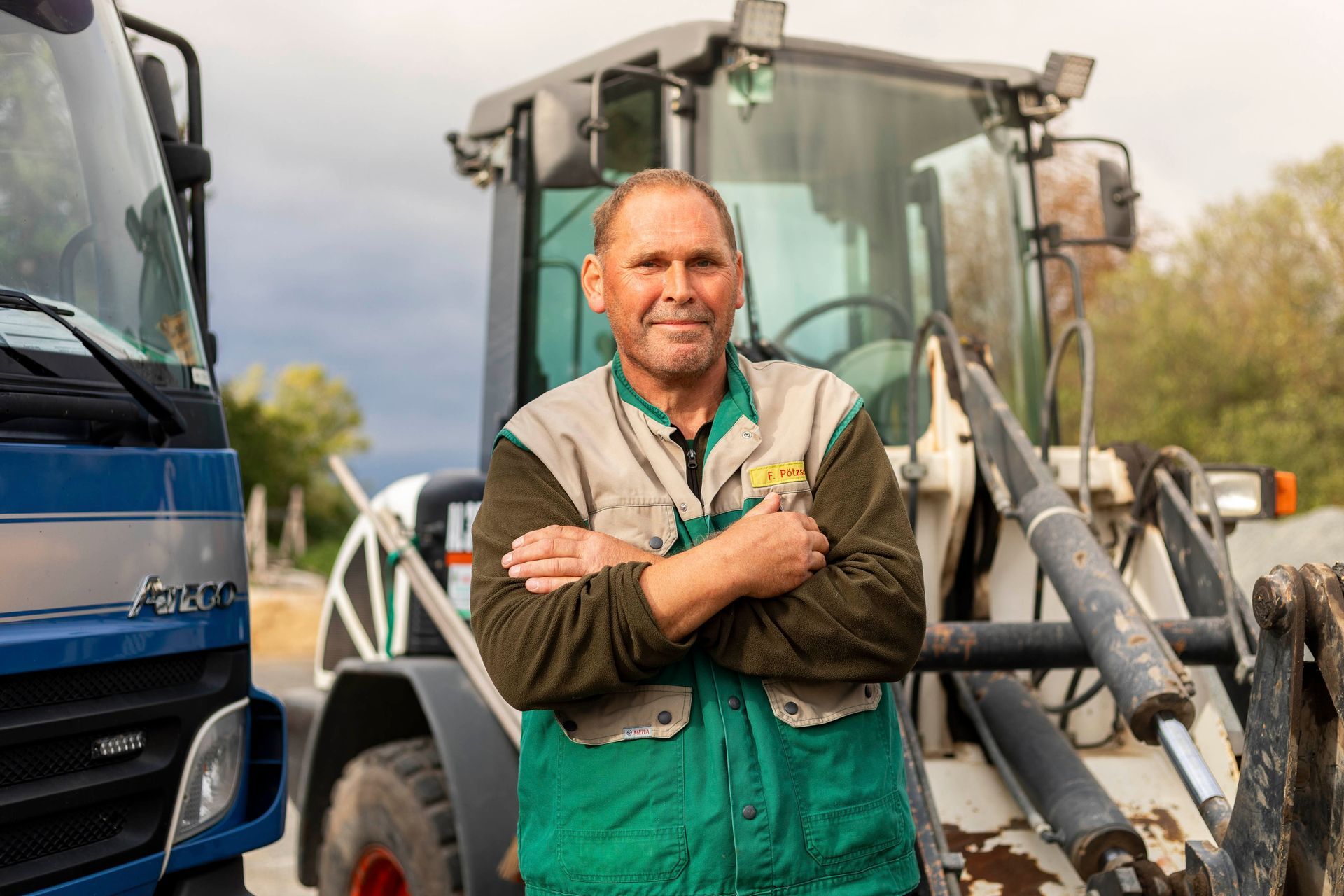 ein mann steht vor einem traktor und trägt eine jacke mit dem schriftzug j.a. schmidt