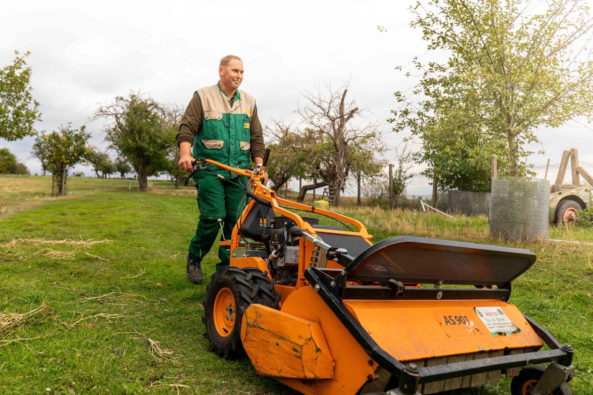 ein Mann fährt einen orangefarbenen Traktor mit der Aufschrift as390