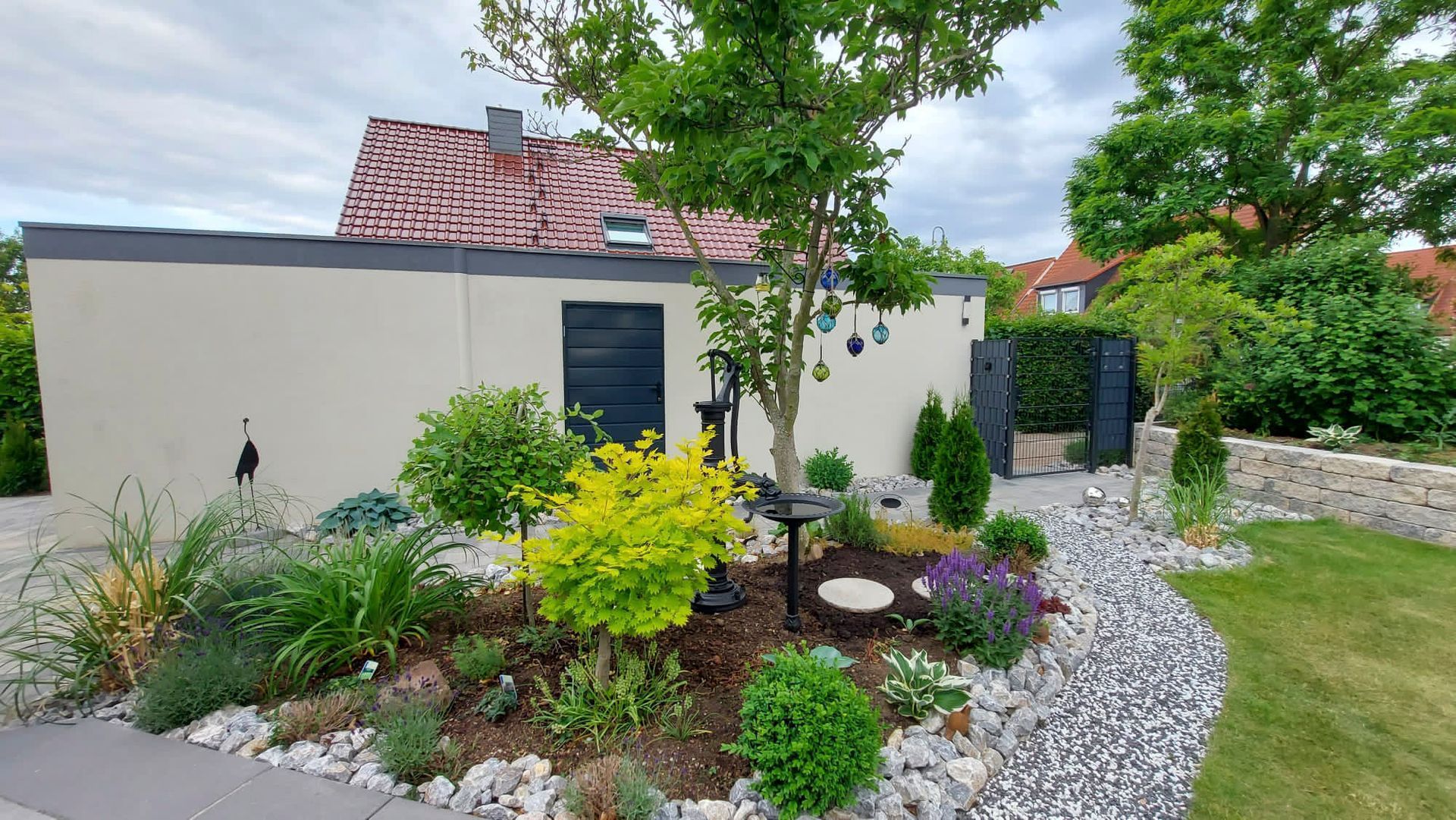 ein Garten mit Bäumen und Steinen vor einem Haus