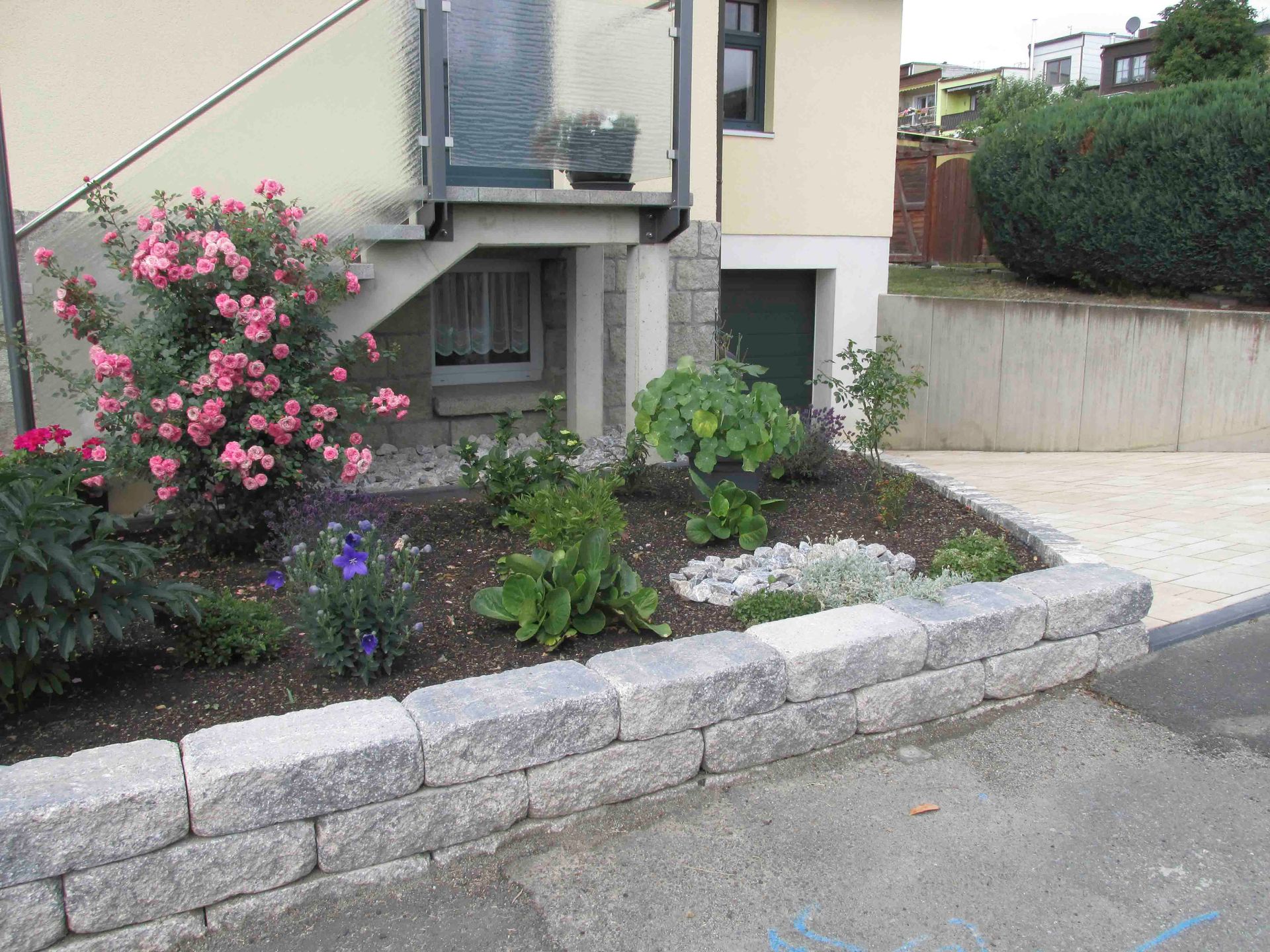 ein Garten mit Blumen und Steinen vor einem Haus
