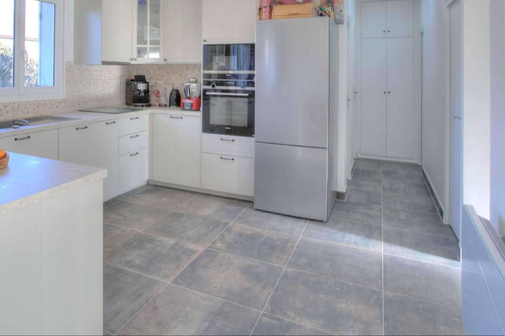 Carrelage en teintes de gris, carreaux grand format, sur le sol d'une cuisine