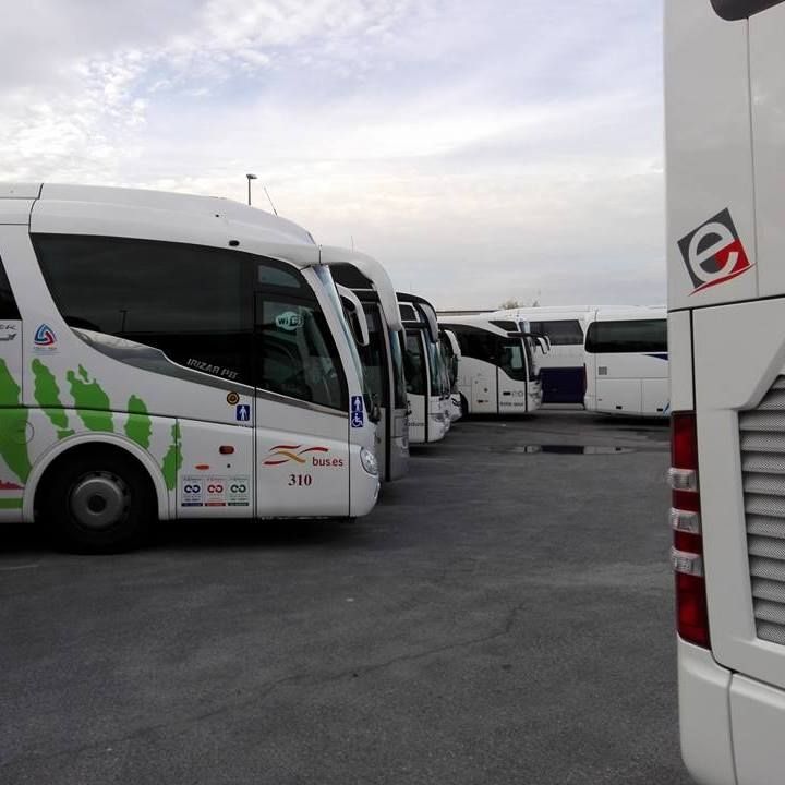 Una fila de autobuses están estacionados en un estacionamiento