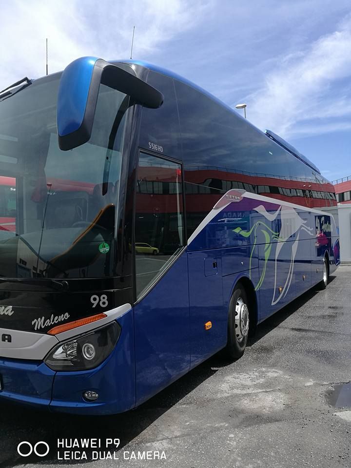 Un autobús azul está estacionado frente a un edificio.