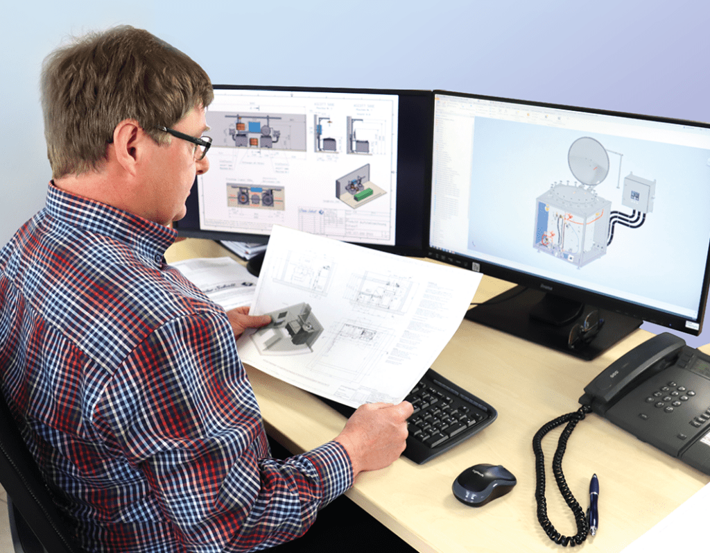 ein Mann sitzt an seinem Schreibtisch vor zwei Monitoren