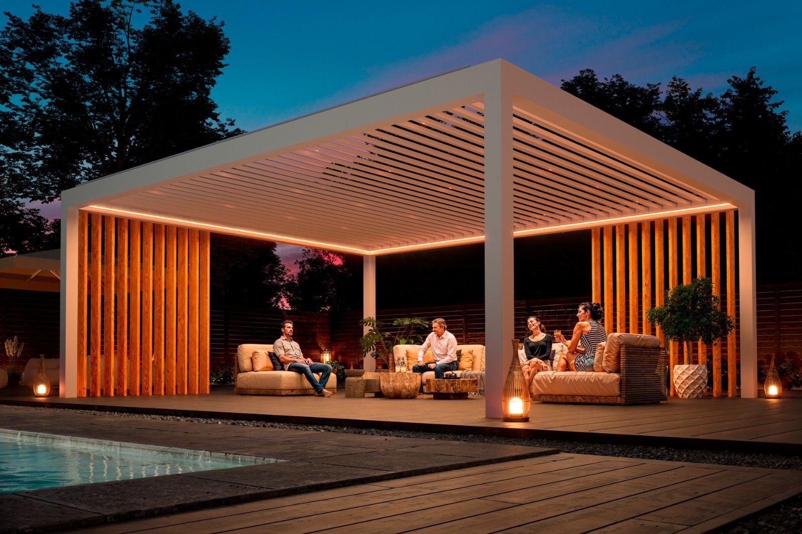 Pérgola con vigas iluminadas sobre un patio con mobiliario, contra un cielo azul crepuscular.