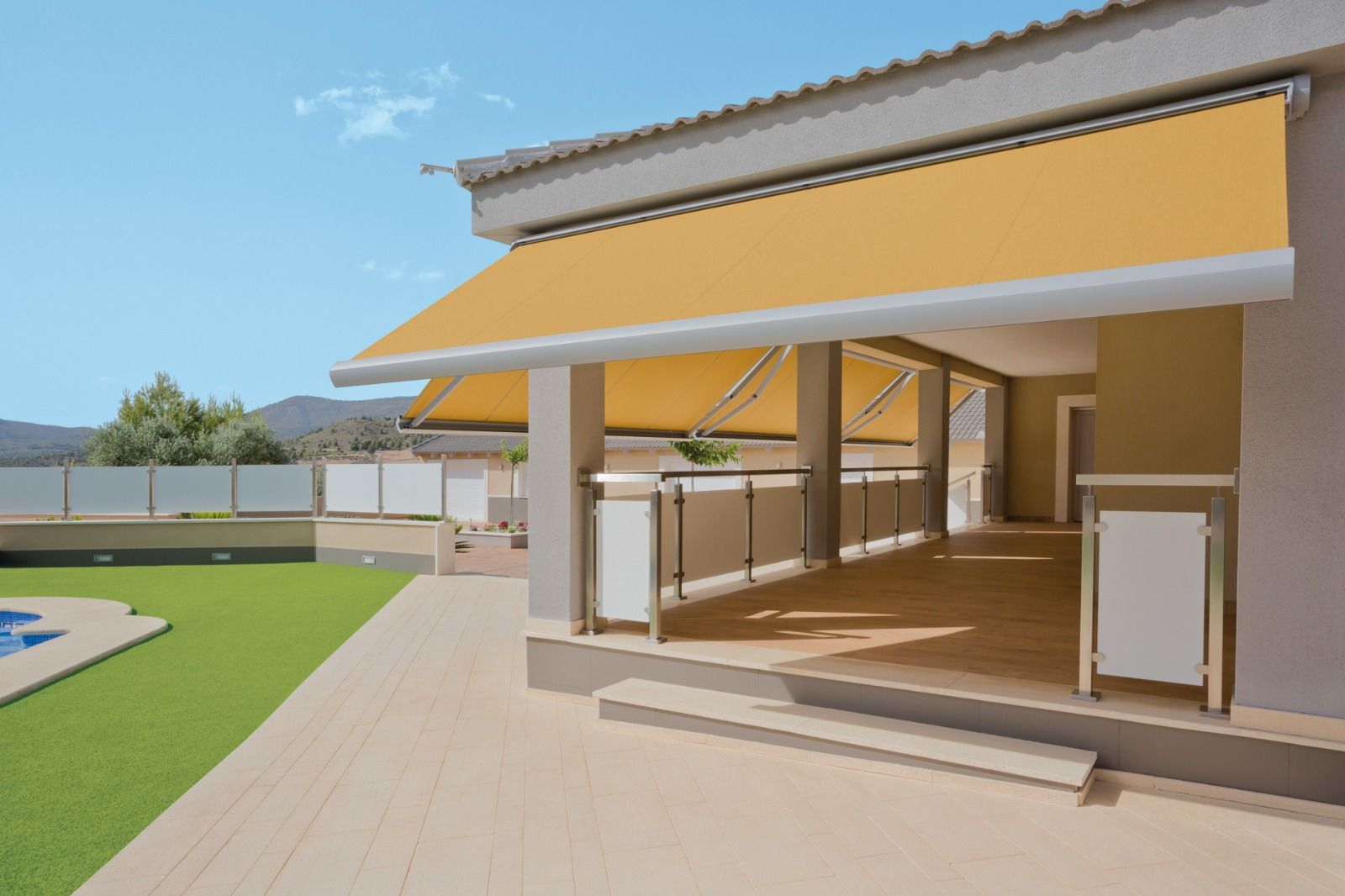 Piscina con toldo, tumbonas, jardín, agua azul y valla gris. Día soleado.