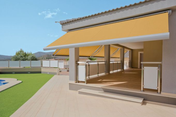 Piscina con toldo, tumbonas, jardín, agua azul y valla gris. Día soleado.