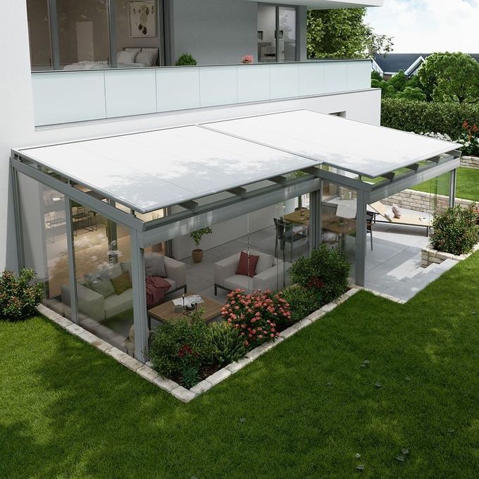 Patio al aire libre con sombrillas naranjas, marco blanco y vista a árboles y edificios.