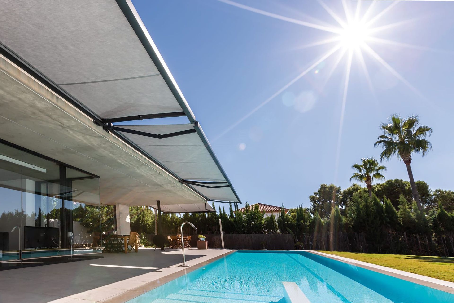 Casa moderna con piscina, patio cubierto y un sol radiante. Cielo azul y palmeras de fondo.