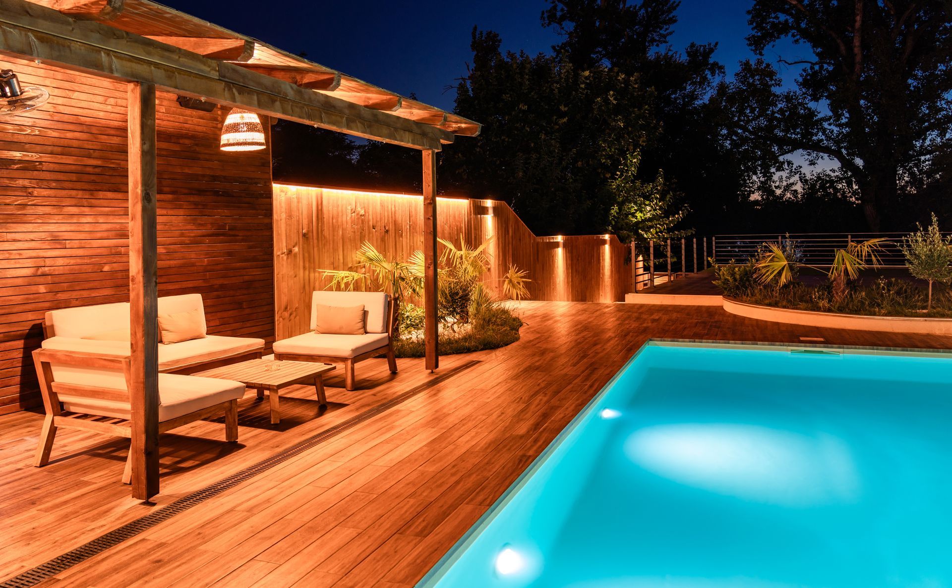 Une piscine la nuit avec un abri en bois