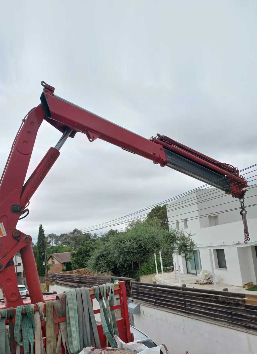 Una grulla roja está sentada frente a un edificio blanco.