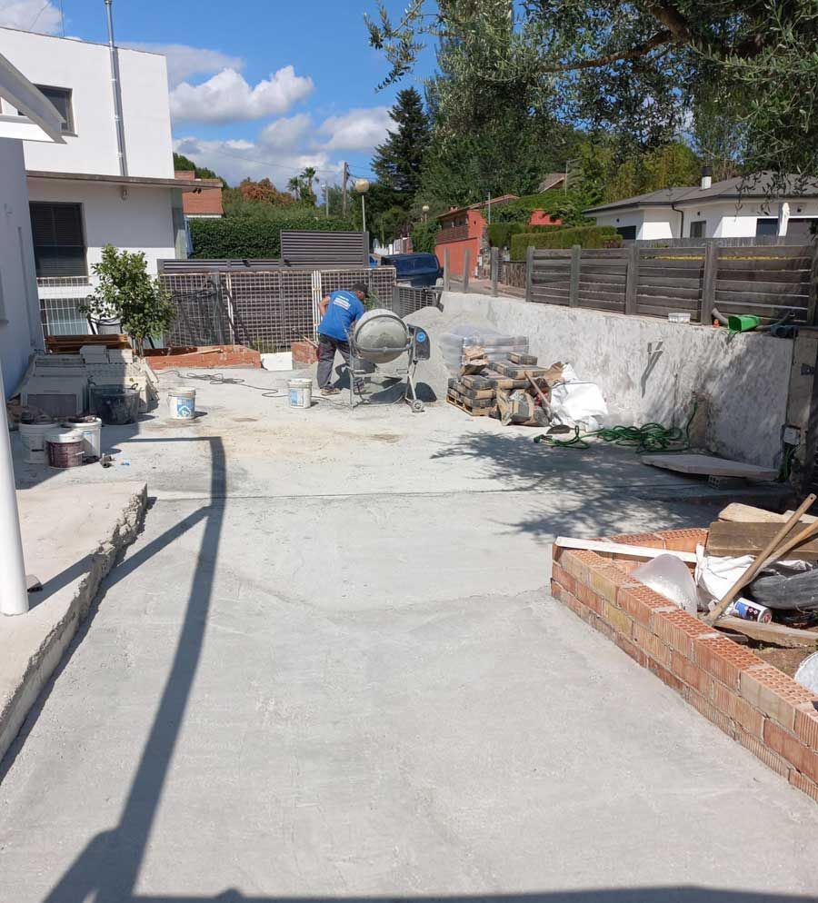 Se está utilizando una hormigonera para mezclar hormigón en un patio trasero.