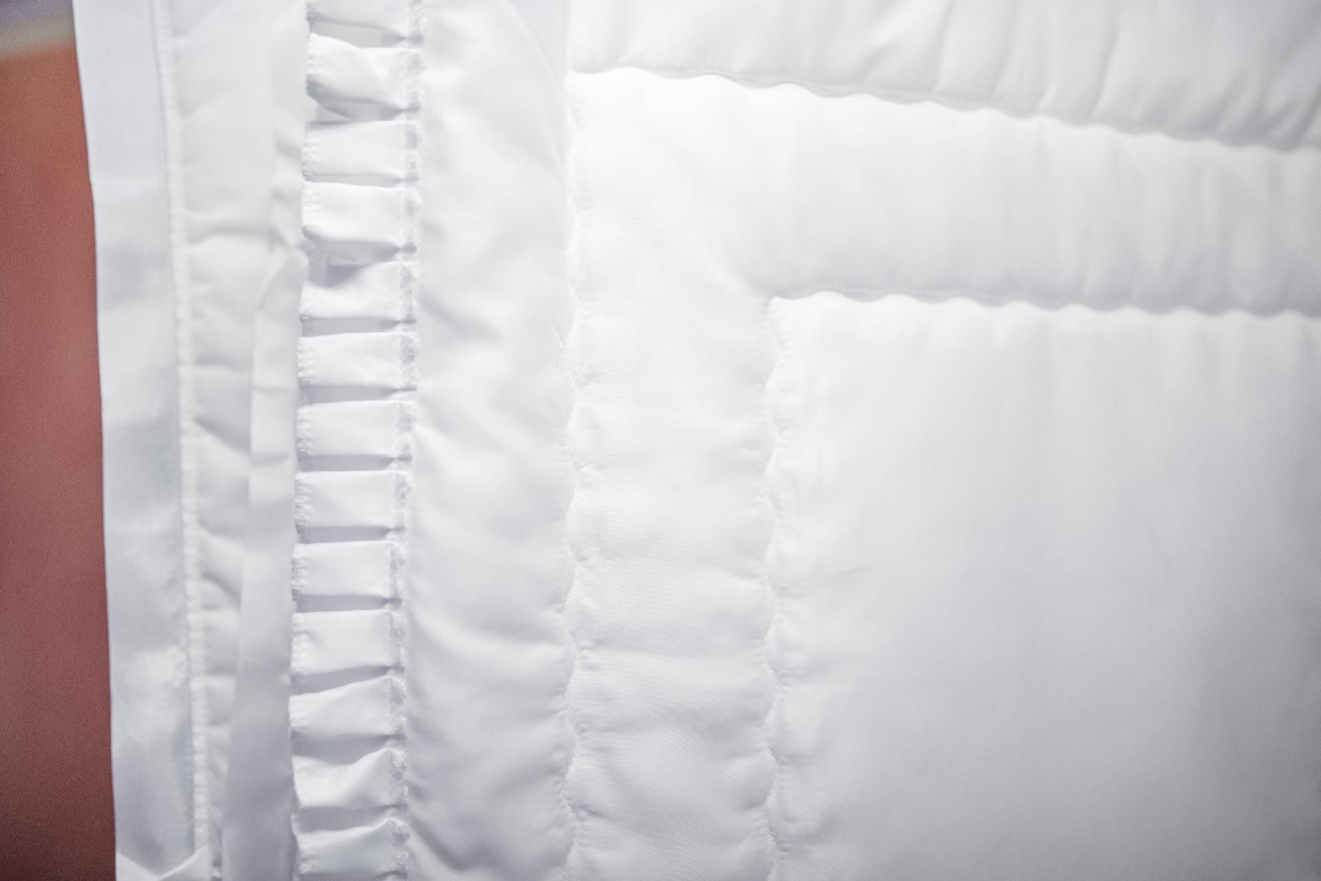 Decken für den Sarg Nahaufnahme eines weißen Steppstoffs mit gestickten Mustern und Rüschenranddetails.