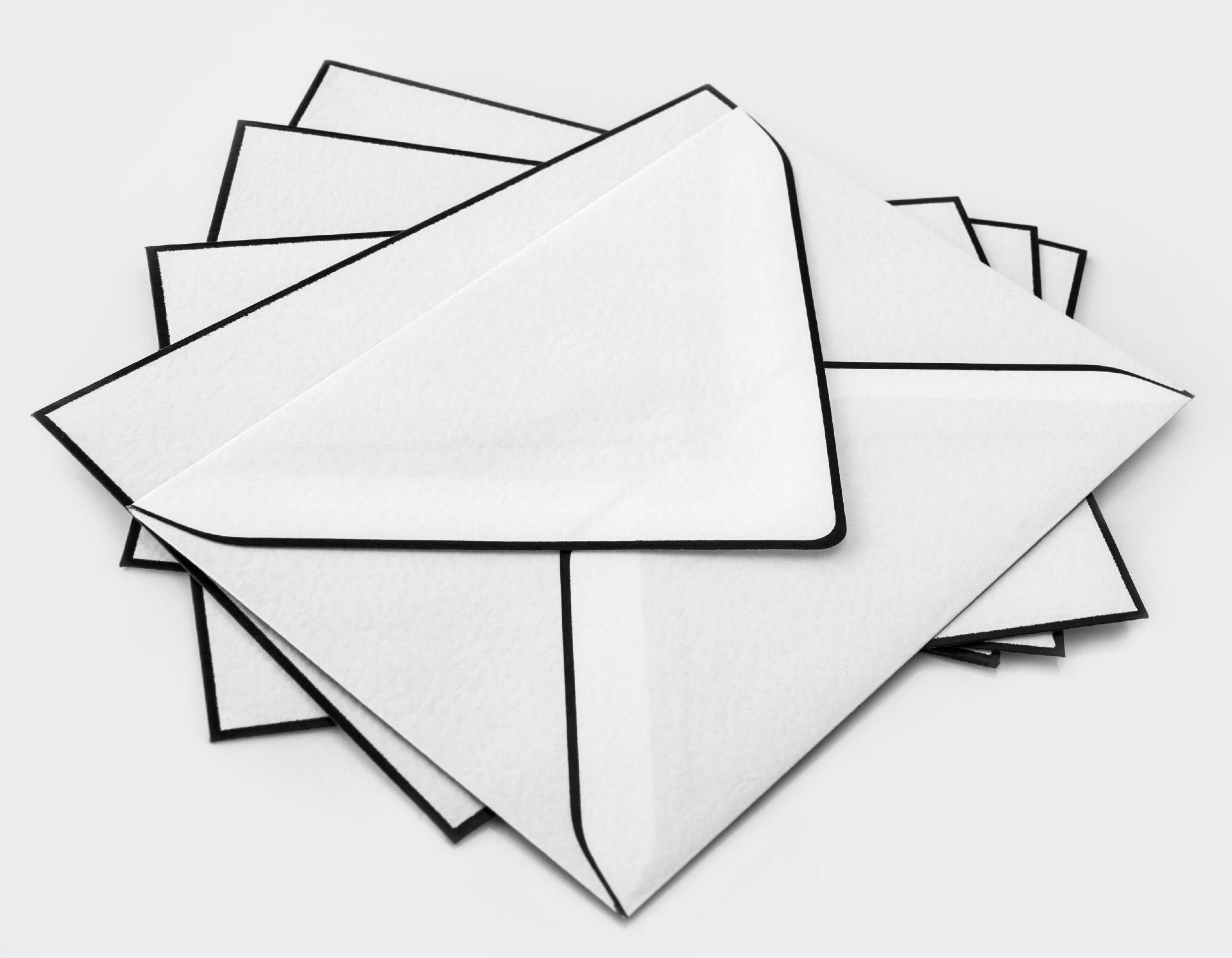 Weiße Umschläge mit schwarzem Rand Weiße Umschläge mit schwarzem Rand liegen auf einer weißen Oberfläche übereinander
