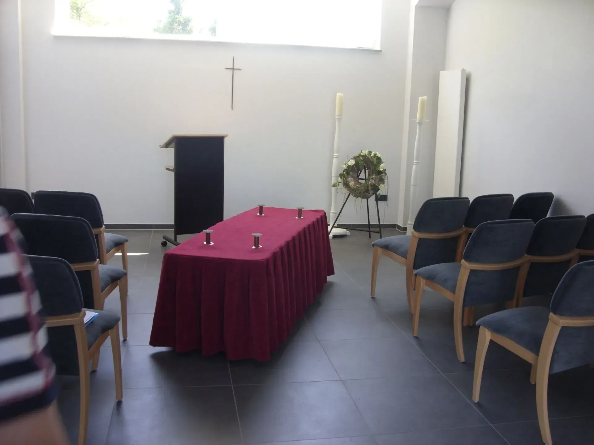 Trauerhalle mit Sarg, Stuhlreihen und Rednerpult.