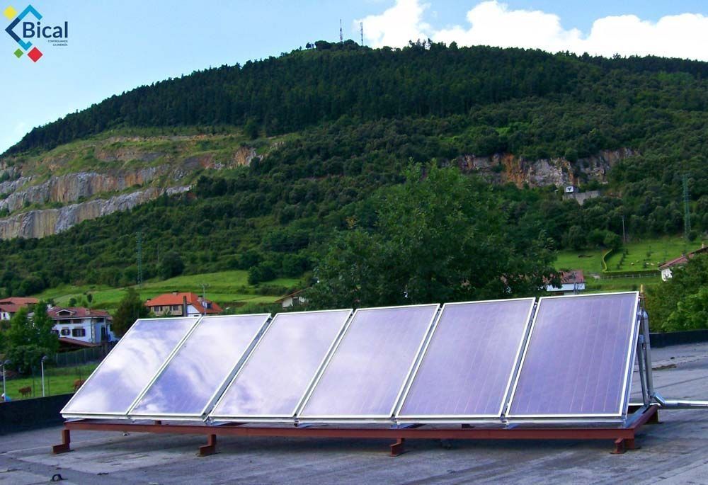 Una fila de paneles solares en un tejado con una montaña al fondo