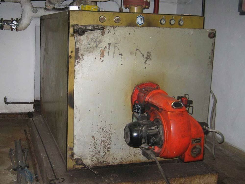 Una caldera con un quemador rojo está en una habitación.