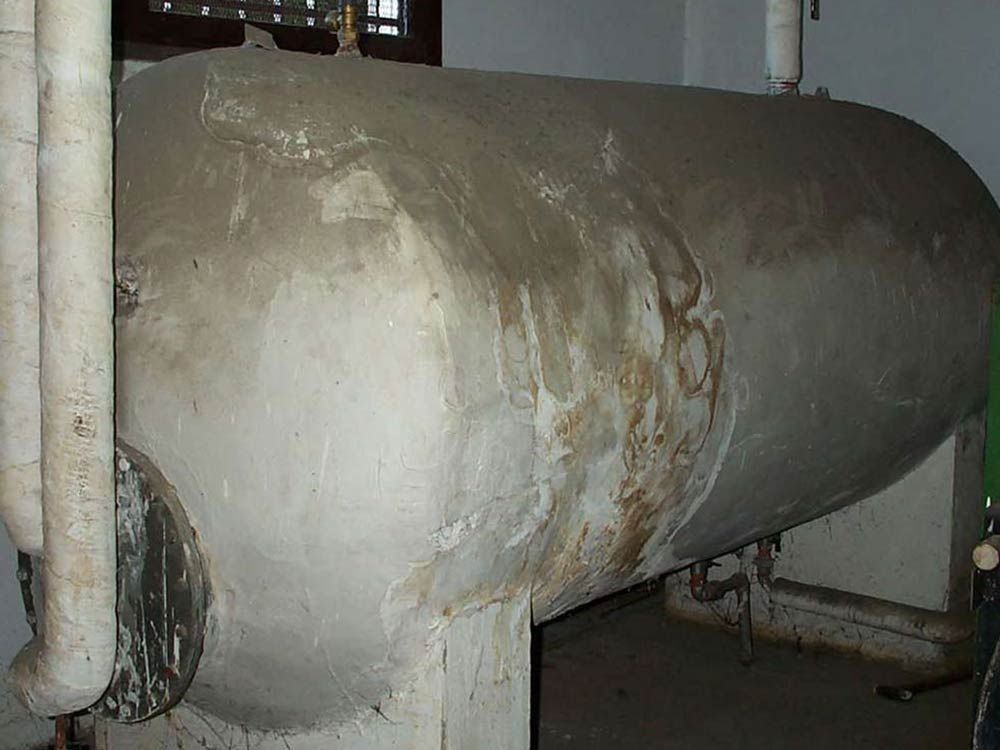 Un gran tanque gris está sentado en una habitación al lado de una ventana.