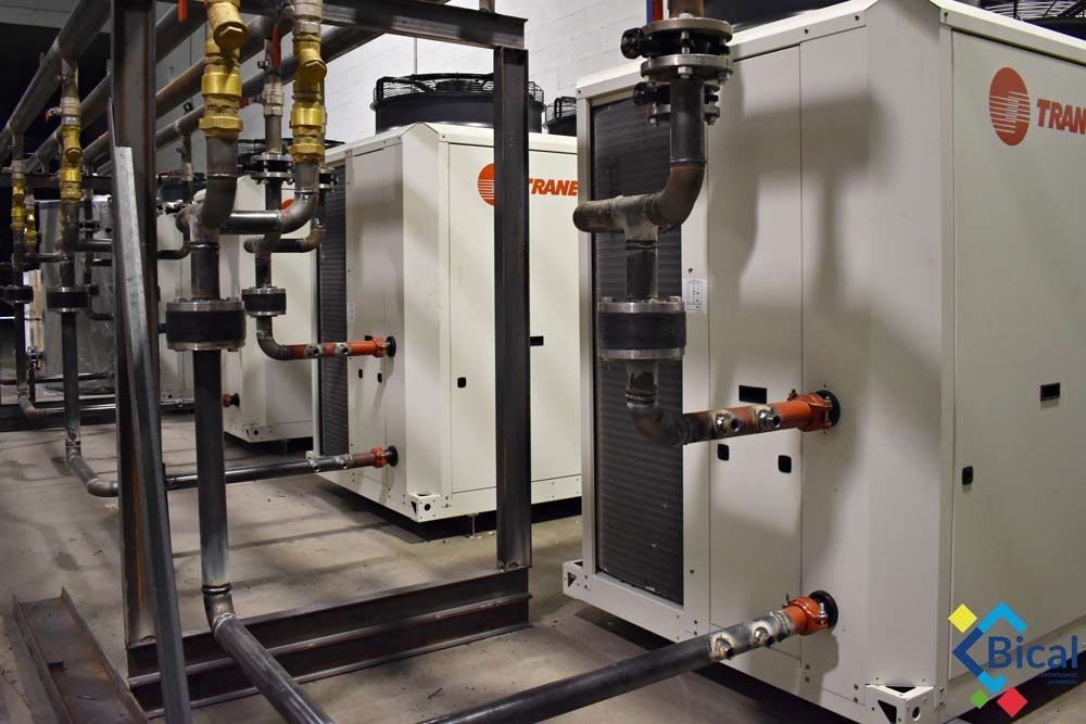 Una hilera de edificios blancos con tuberías que salen de ellos.